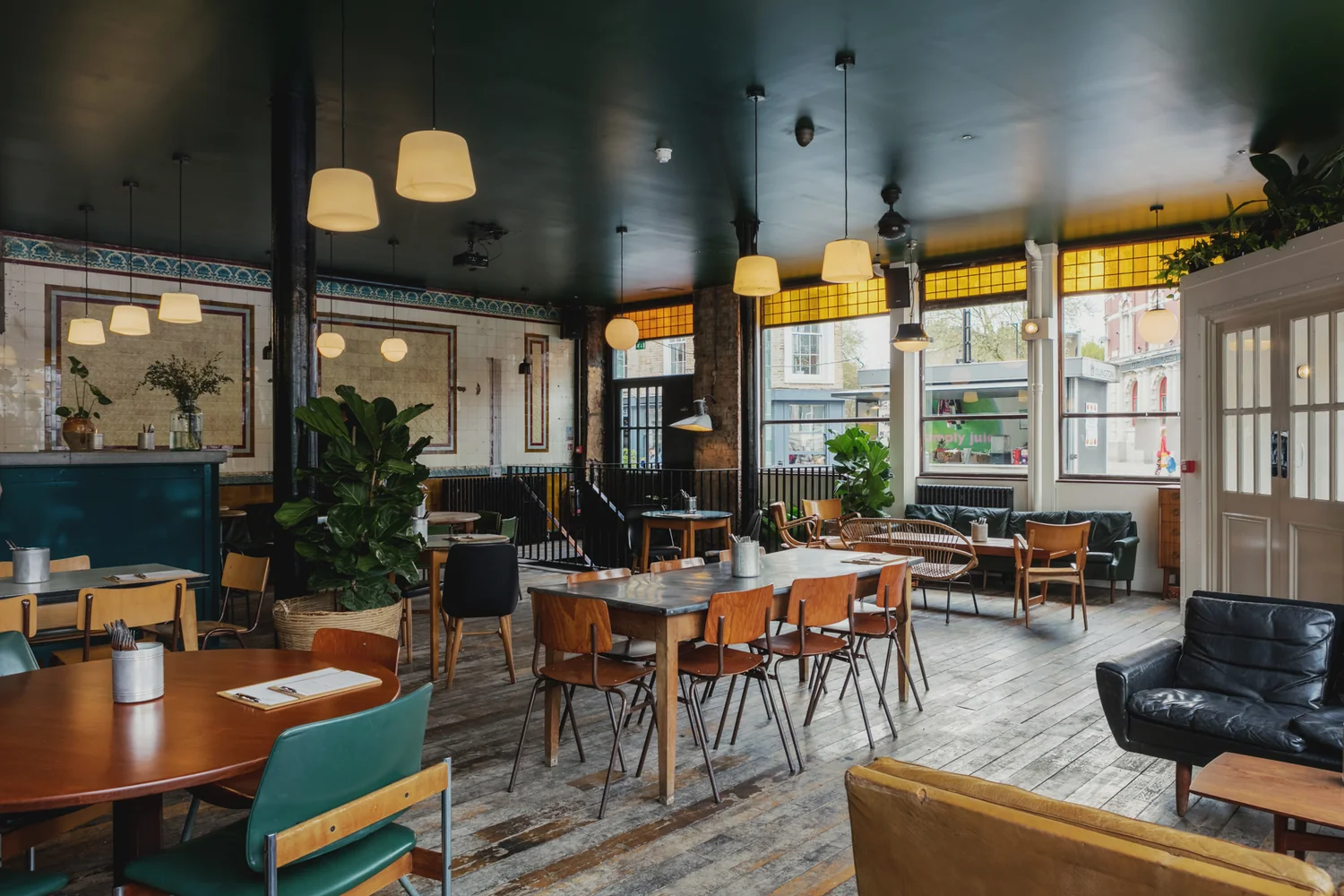 Traditional pub interior with mixed vintage seating, hanging lights and leafy plants