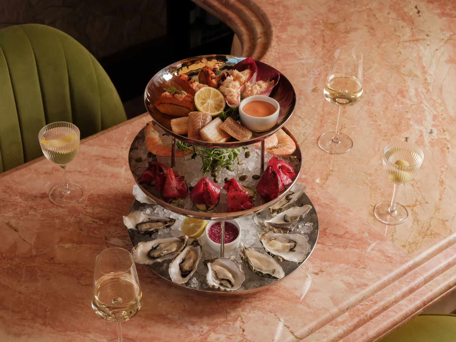 Tiered seafood platter with oysters and champagne on a marble table